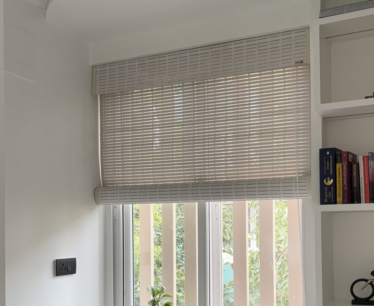 Woven bamboo roller blind over a window with plants on the sill