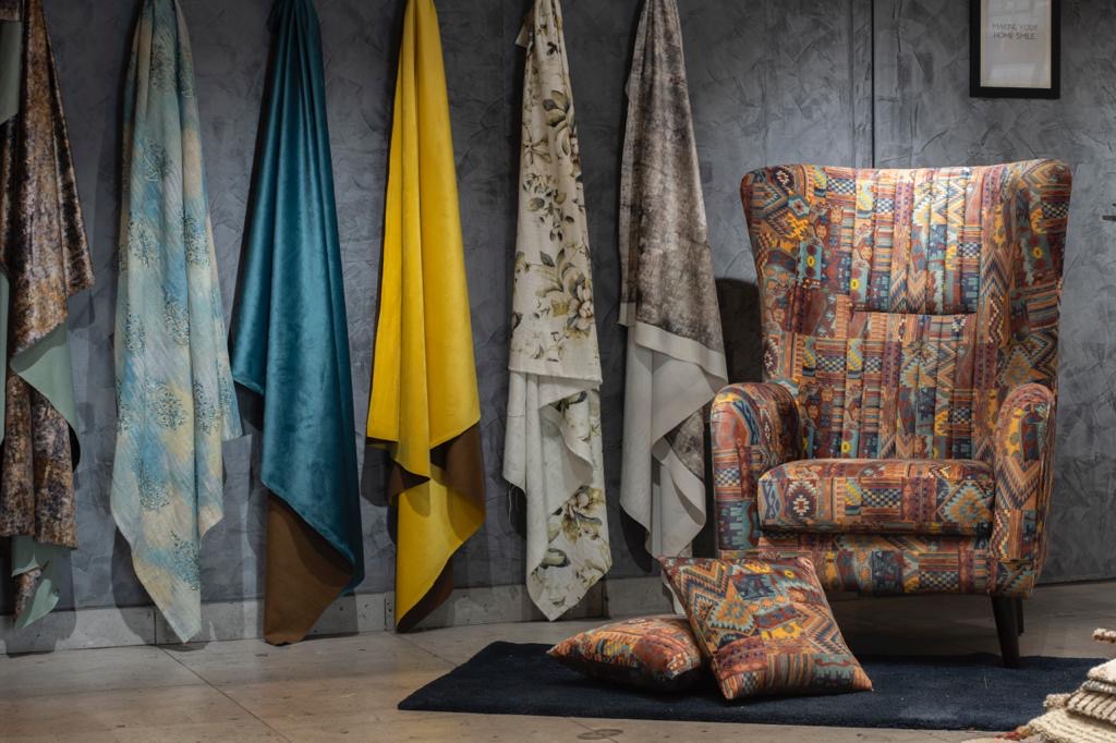 Drapery fabrics hanging beside an upholstered wing chair